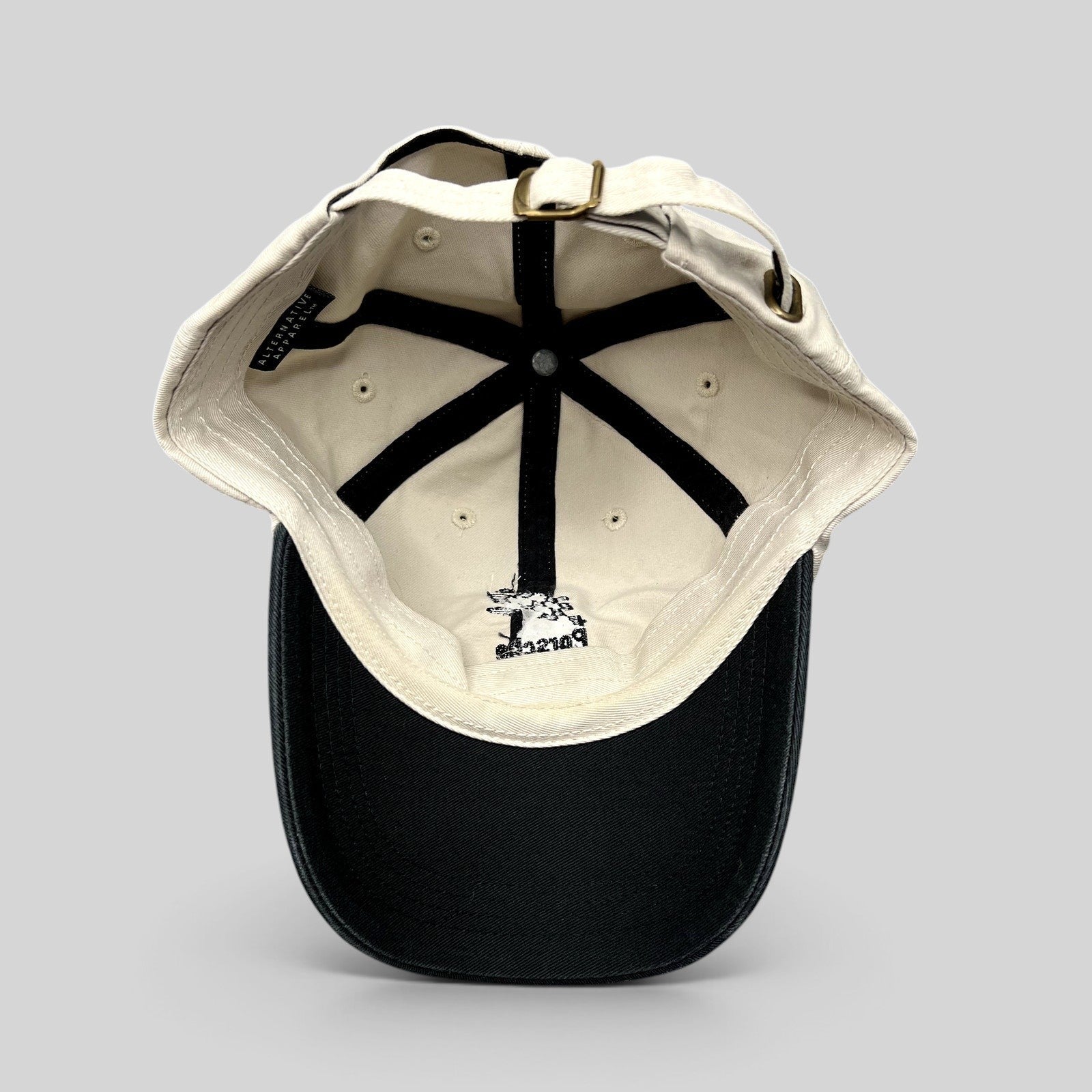 Raree Finds Porsche Driving Experience strapback hat in black and cream with brass hardware and interior logo detail.