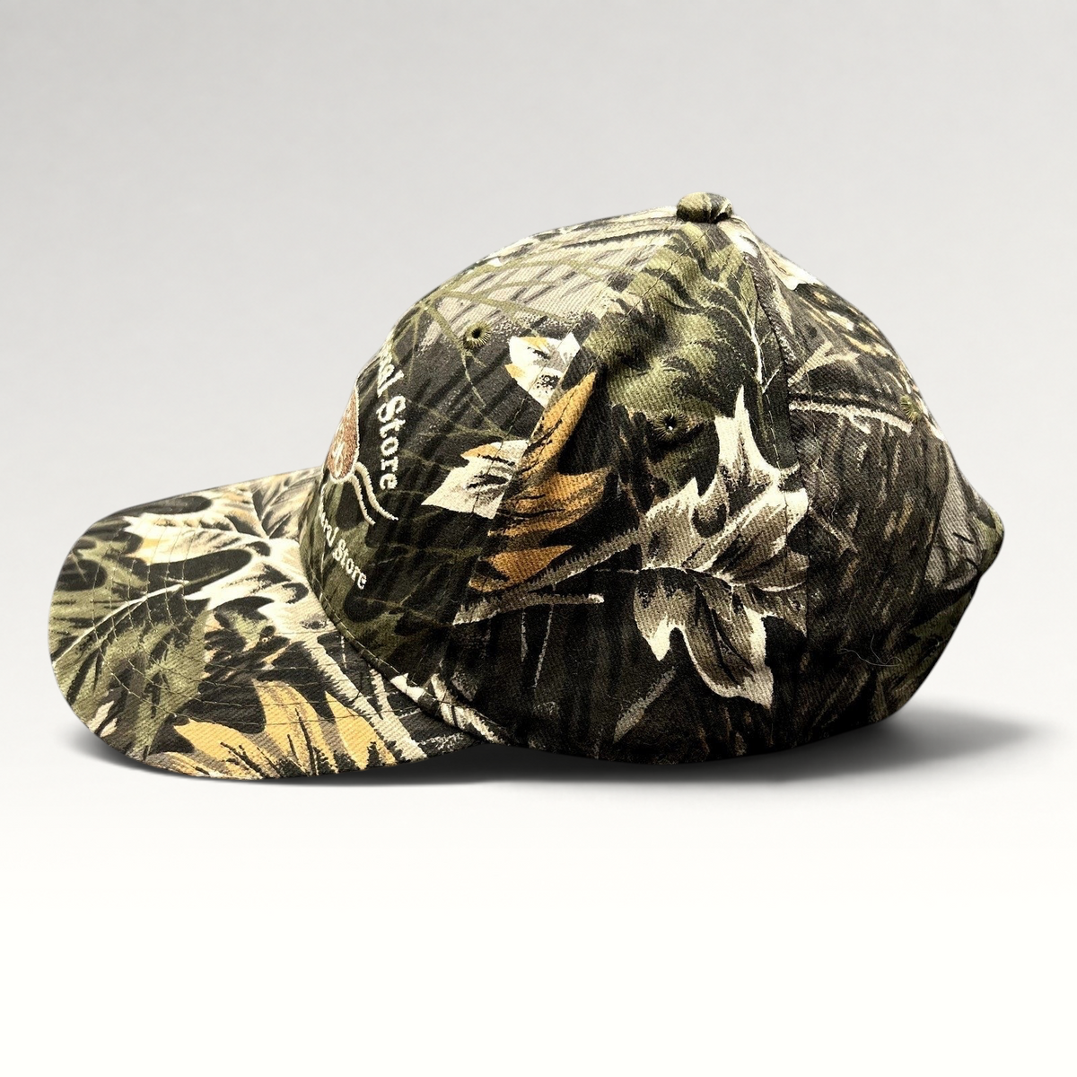 Raree Finds Putney General Store woodland camouflage strapback hat with embroidered Vermont logo and curved brim.
