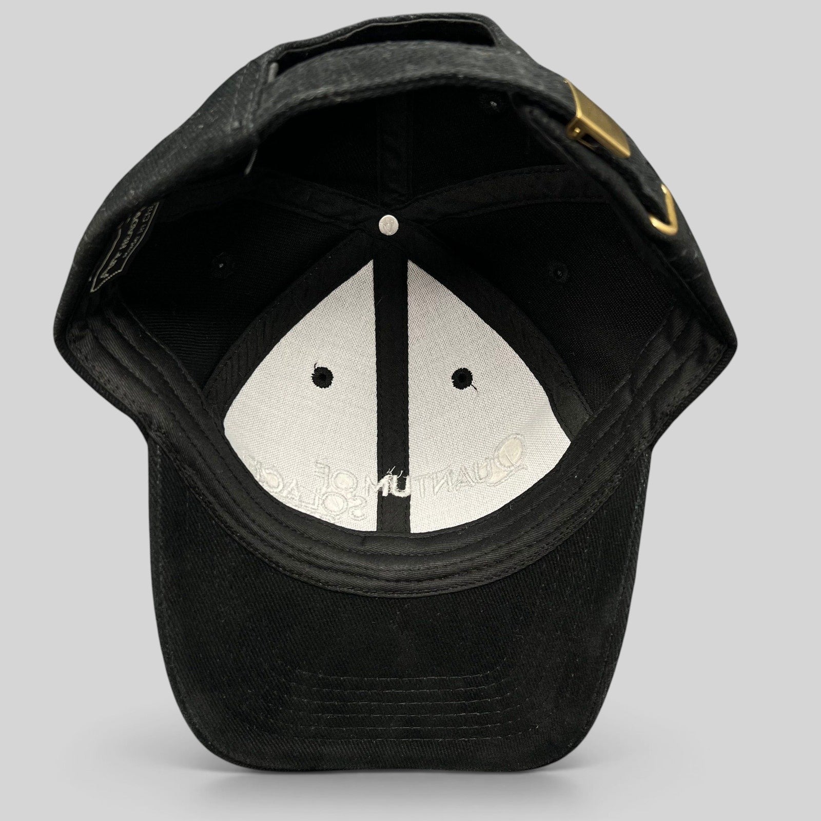 Raree Finds black Quantum of Solace 007 strapback hat showing the interior lining and brass buckle closure.