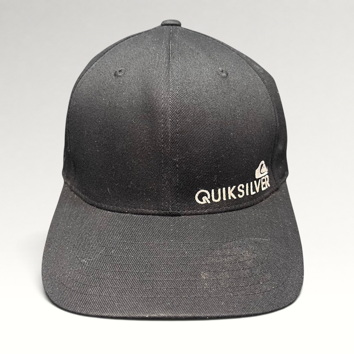 Raree Finds black Quiksilver Flexfit cap with white embroidered mountain and wave logo on a structured crown