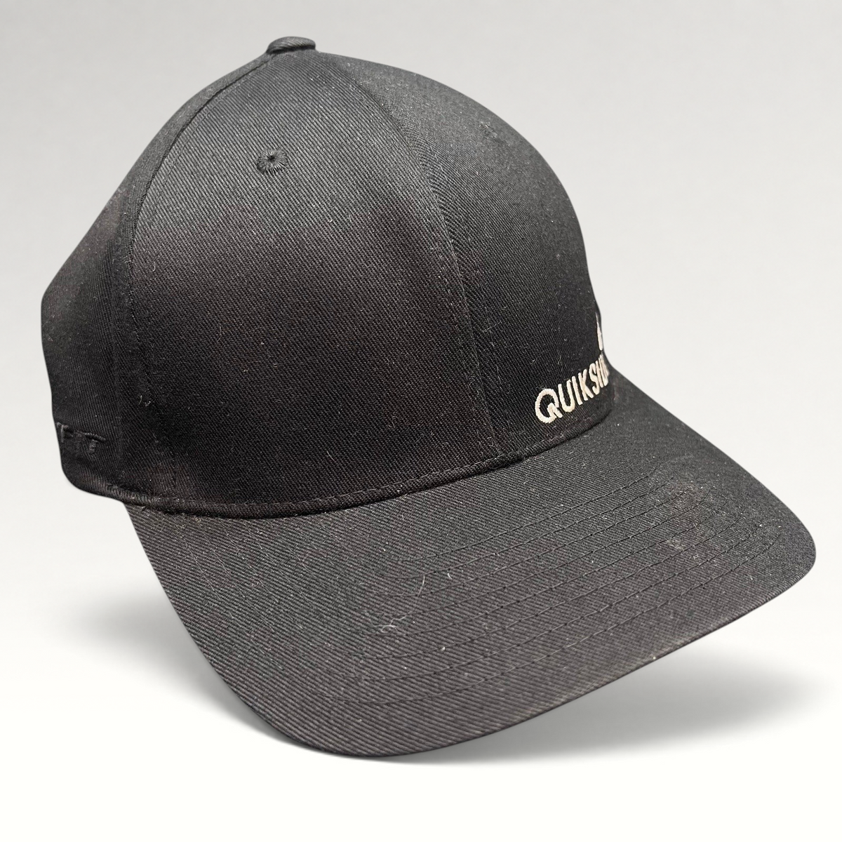 Raree Finds black Quiksilver Flexfit cap with white embroidered logo and structured curved bill for surf and skate wear.