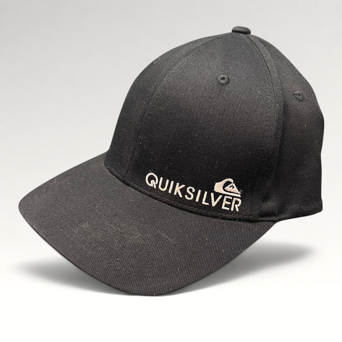 Raree Finds black Quiksilver Flexfit cap with white embroidered mountain and wave logo on a structured curved bill