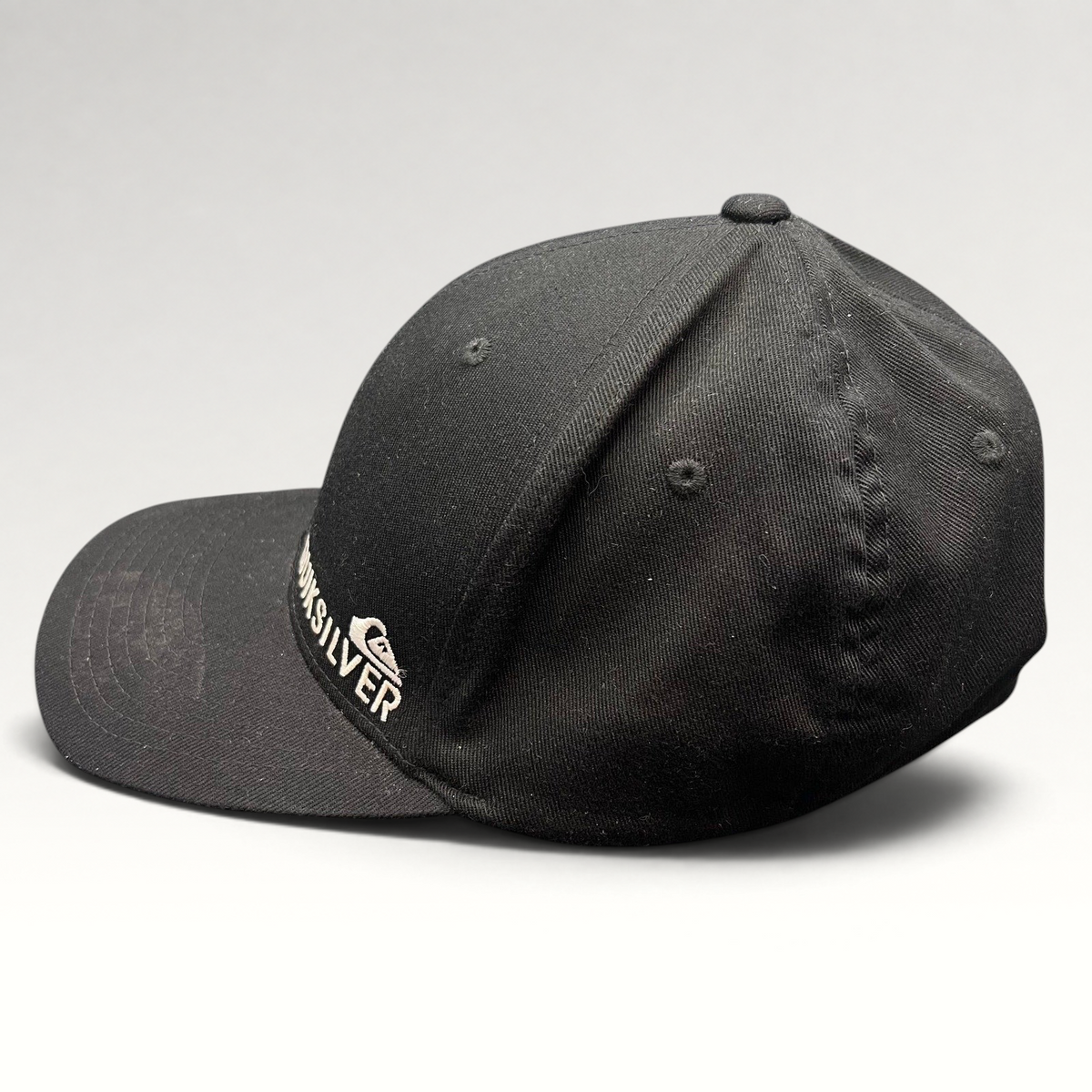 Raree Finds black Quiksilver Flexfit cap with white embroidered mountain and wave logo on a structured crown