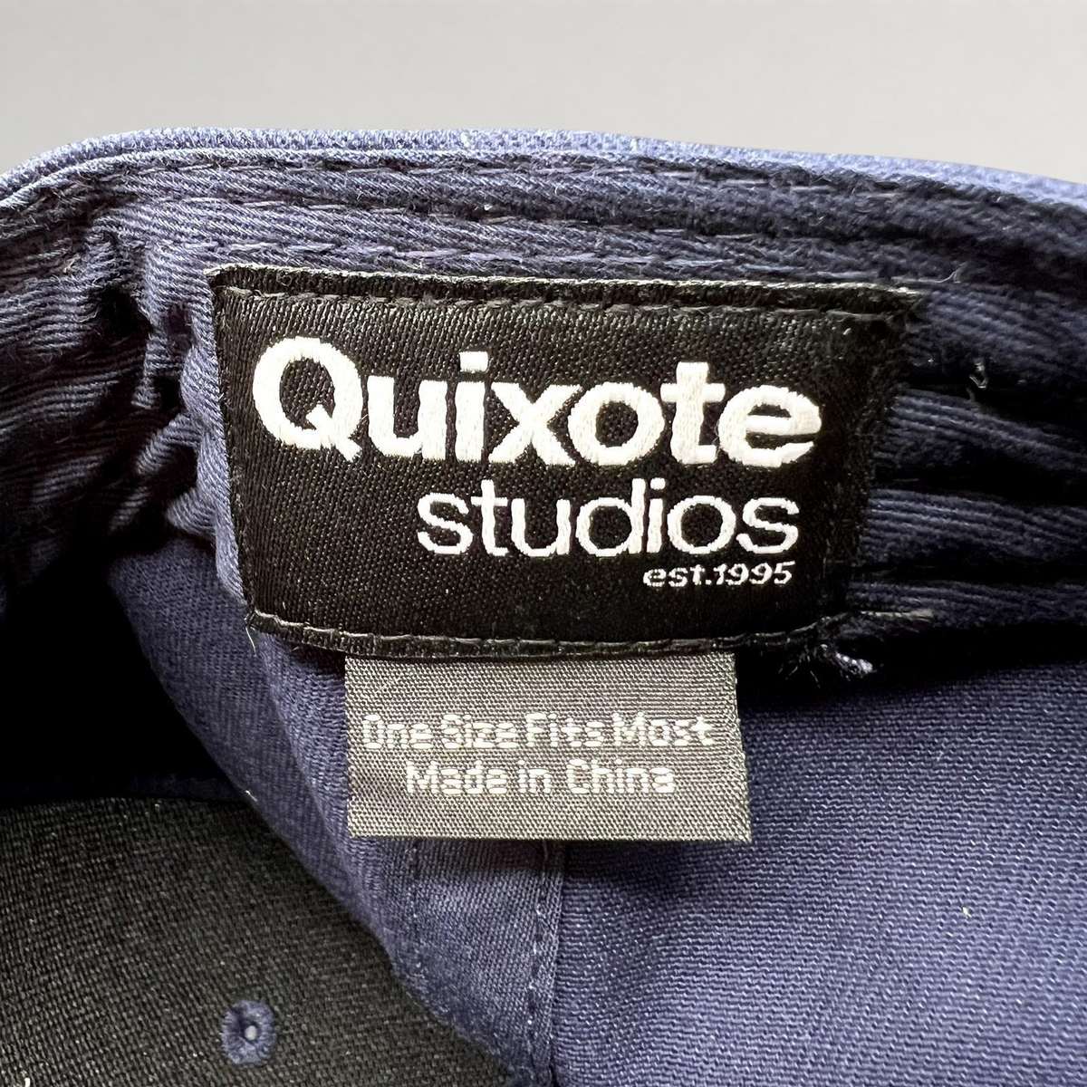 Raree Finds Quixote Studios navy blue snapback hat interior brand label with white text and made in China tag