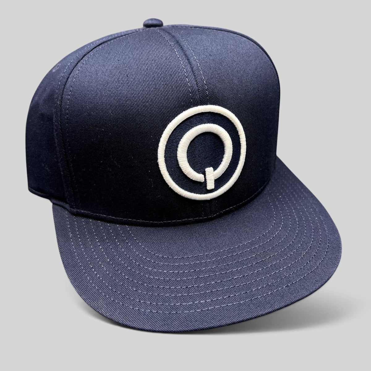 Raree Finds navy blue Quixote Studios snapback hat with a white embroidered circular Q logo and flat brim