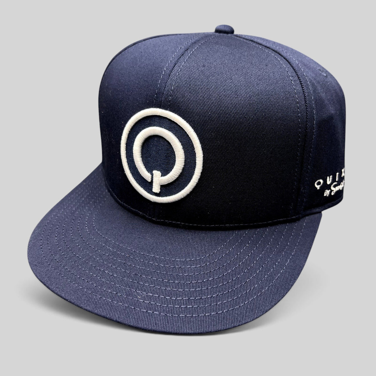 Raree Finds navy blue Quixote Studios snapback hat with a white embroidered circular Q logo and flat brim