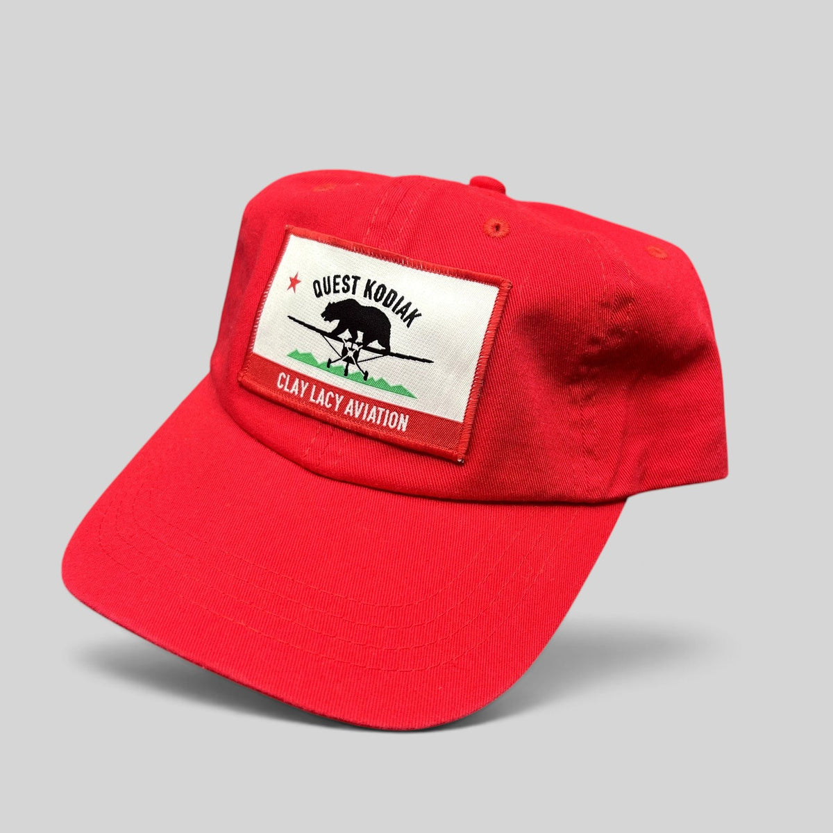 Raree Finds bright red cotton strapback hat with a woven Quest Kodiak and Clay Lacy Aviation aircraft patch