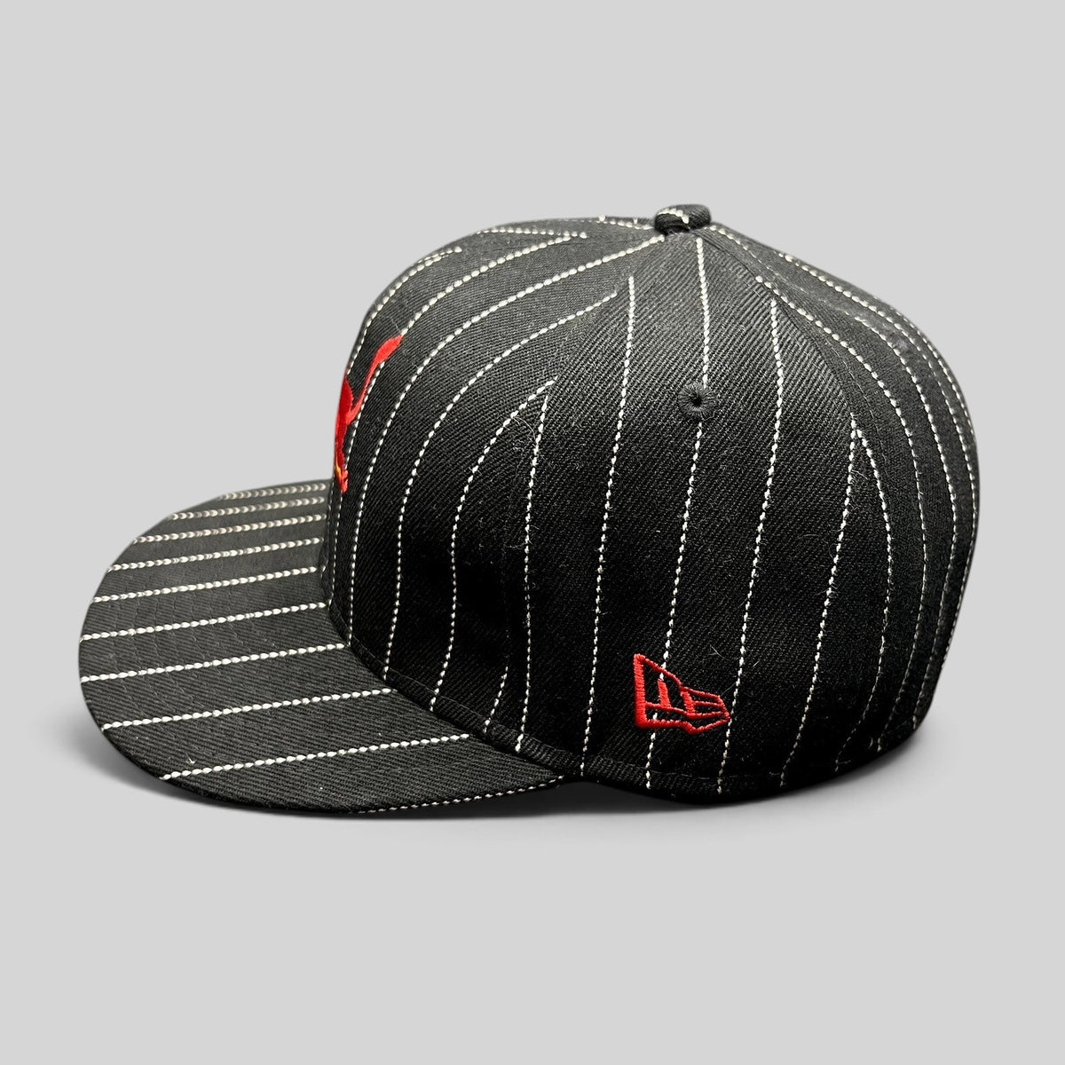 Raree Finds black and white pinstripe New Era 59FIFTY fitted hat with red embroidered Red Bull logo on side profile