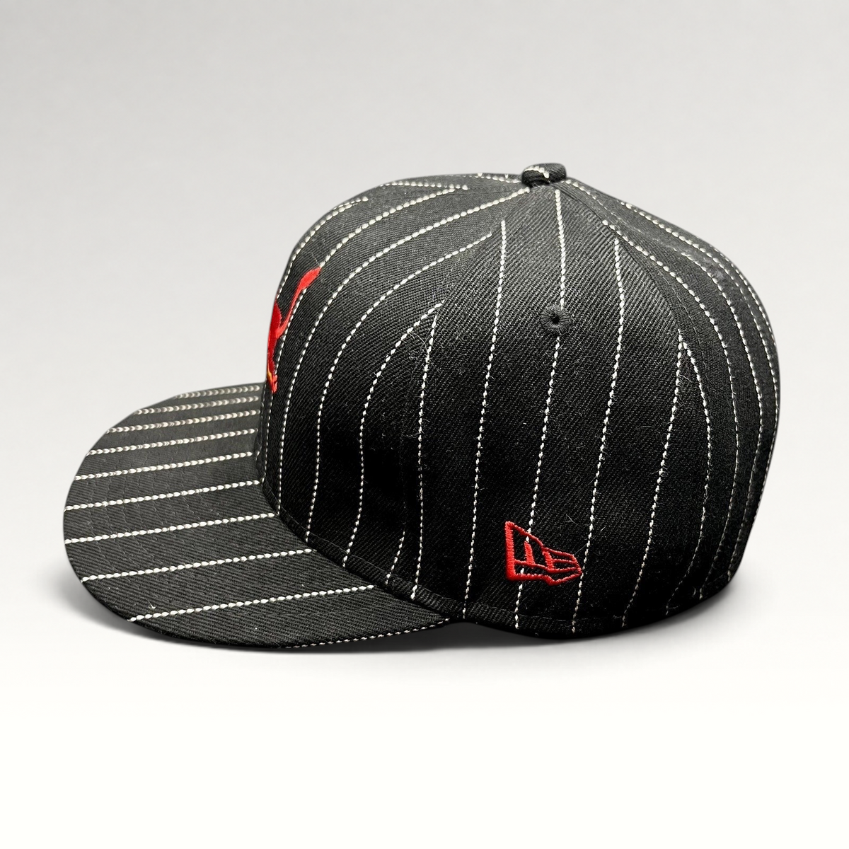 Raree Finds black and white pinstripe New Era 59FIFTY fitted hat with red embroidered Red Bull logo on side profile