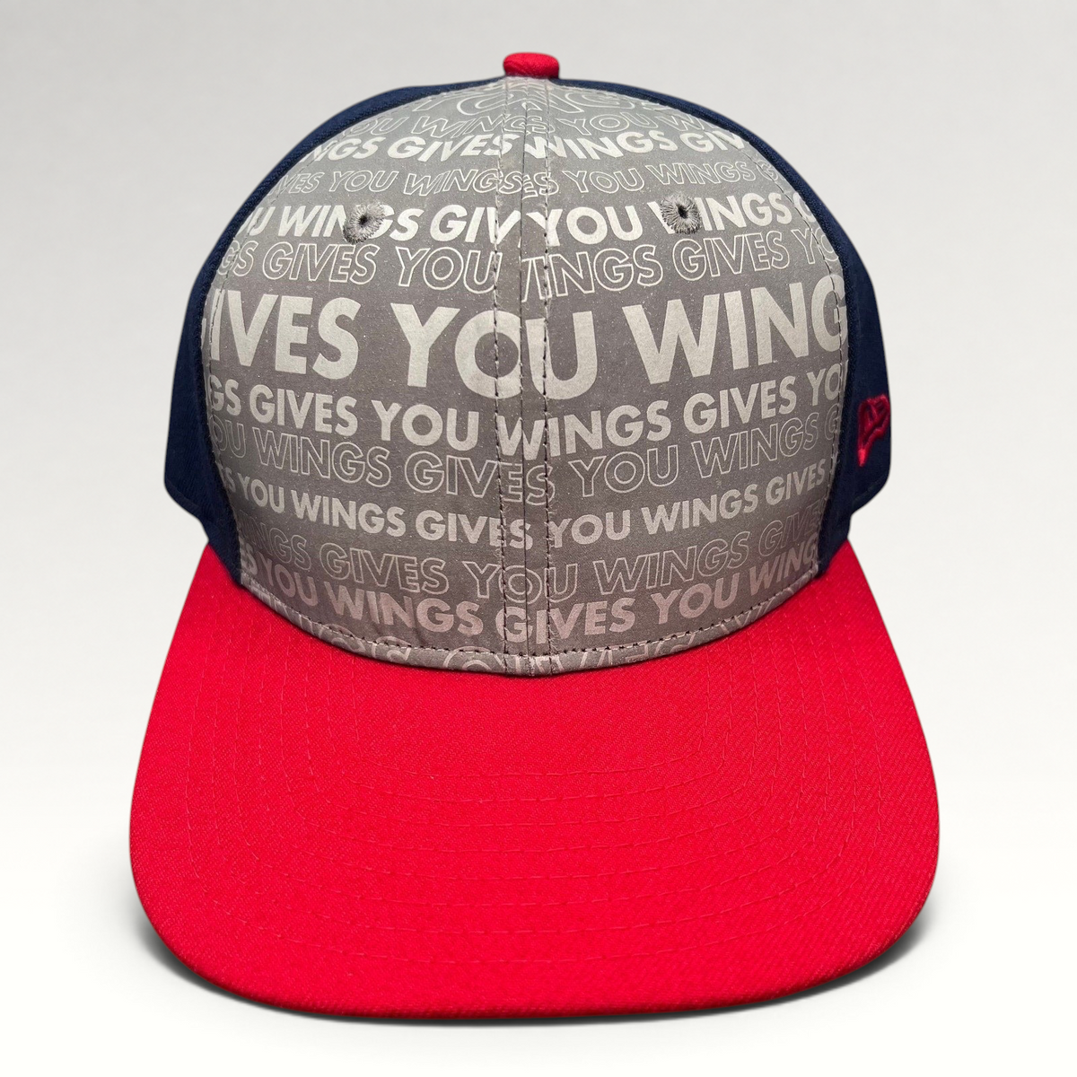 Raree Finds Red Bull Gives You Wings snapback hat by New Era featuring a grey slogan print, navy panels, and red brim.