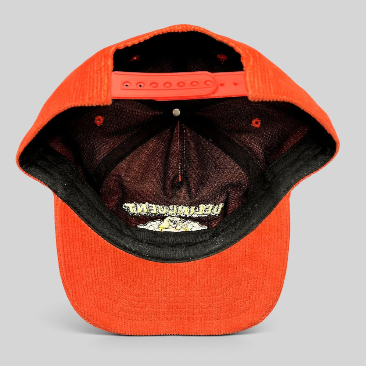 Raree Finds Delinquent Bros red corduroy snapback cap showing the interior crown, adjustable strap, and embroidery.