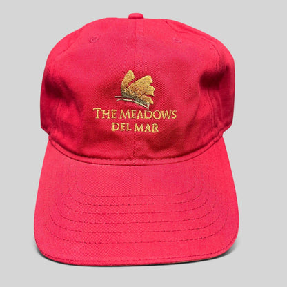 Raree Finds red cotton twill golf cap featuring The Meadows Del Mar embroidered logo and golden flower emblem.