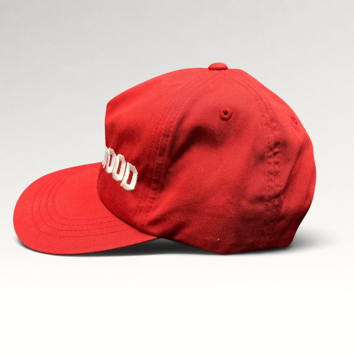 Raree Finds red Yupoong snapback hat with white HOLLYWOOD embroidery and a flat brim in a side profile view.