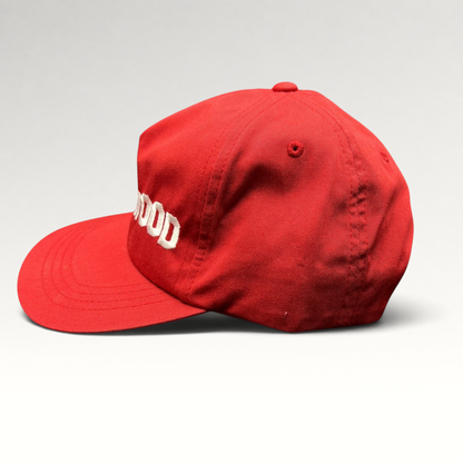 Raree Finds red Yupoong snapback hat with white HOLLYWOOD embroidery and a flat brim in a side profile view.