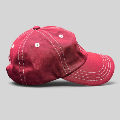Raree Finds red Imperial strapback hat with white contrast stitching and curved brim, side view.