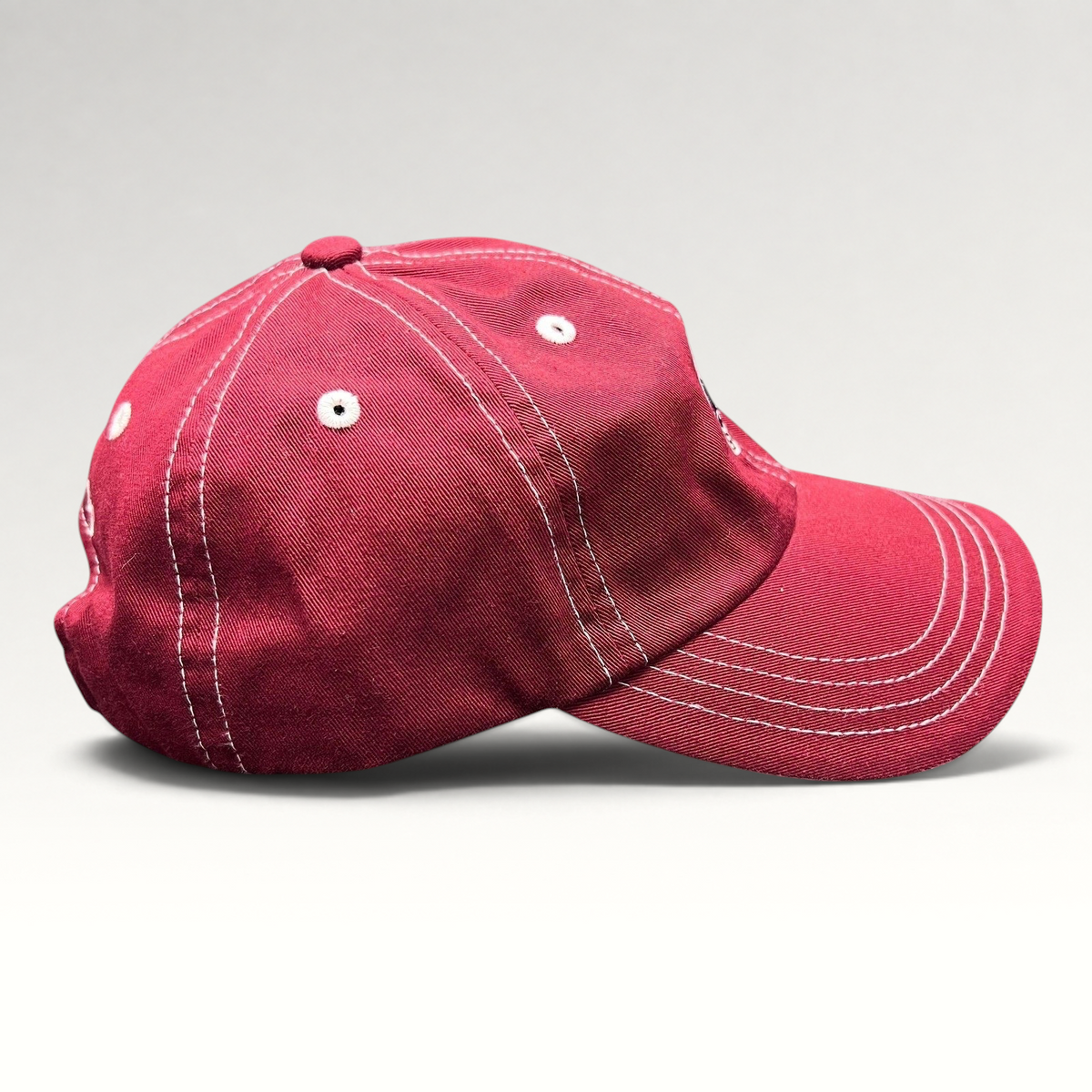 Raree Finds red Imperial strapback hat with white contrast stitching and curved brim, side view.