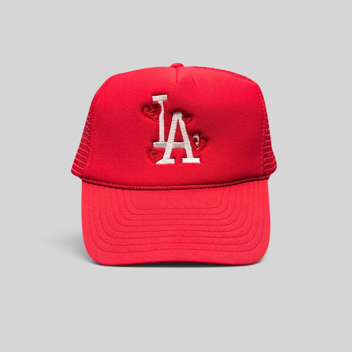 Raree Finds red Nissin Cap trucker hat with white embroidered LA logo and heart accents on a foam front mesh back