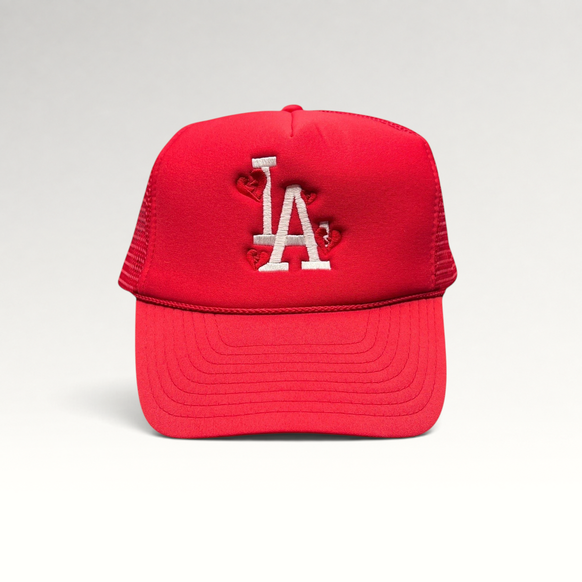 Raree Finds red Nissin Cap trucker hat with white embroidered LA logo and heart accents on a foam front mesh back