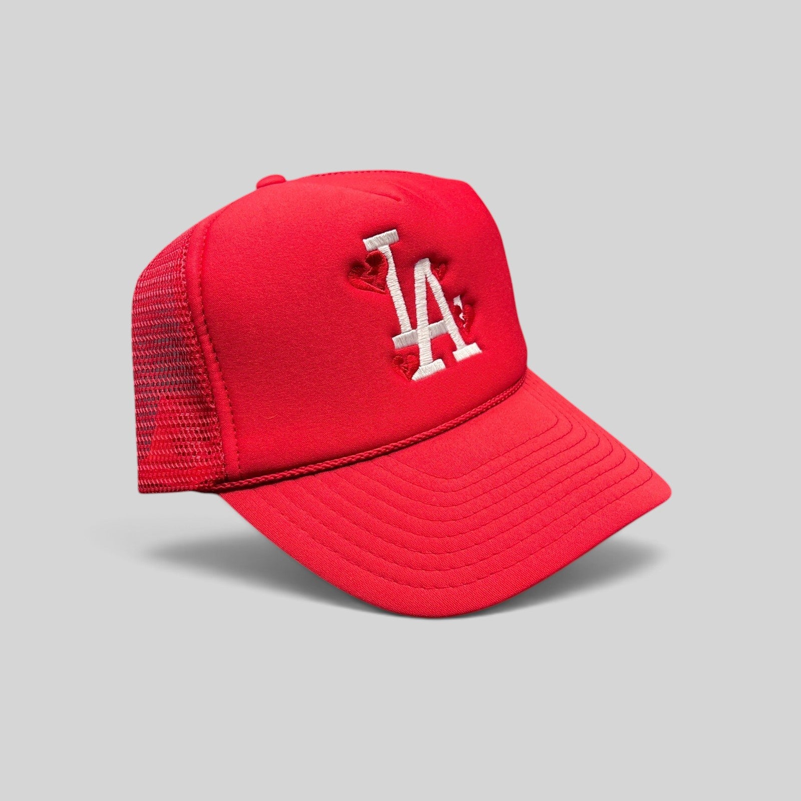 Raree Finds red Nissin Cap trucker hat with white embroidered LA logo and heart details on a foam front mesh back.