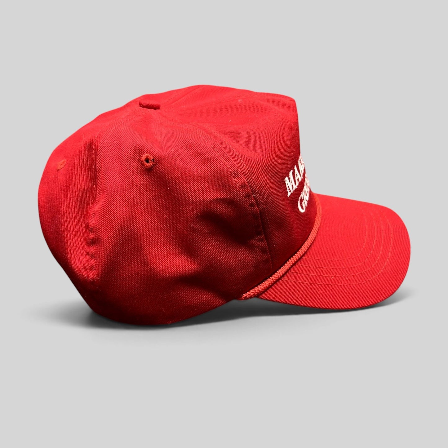 Raree Finds official red MAGA snapback hat with white embroidery and braided rope detail on a black background