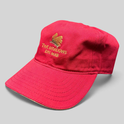 Raree Finds red cotton twill strapback golf cap featuring The Meadows Del Mar embroidered golden flower logo