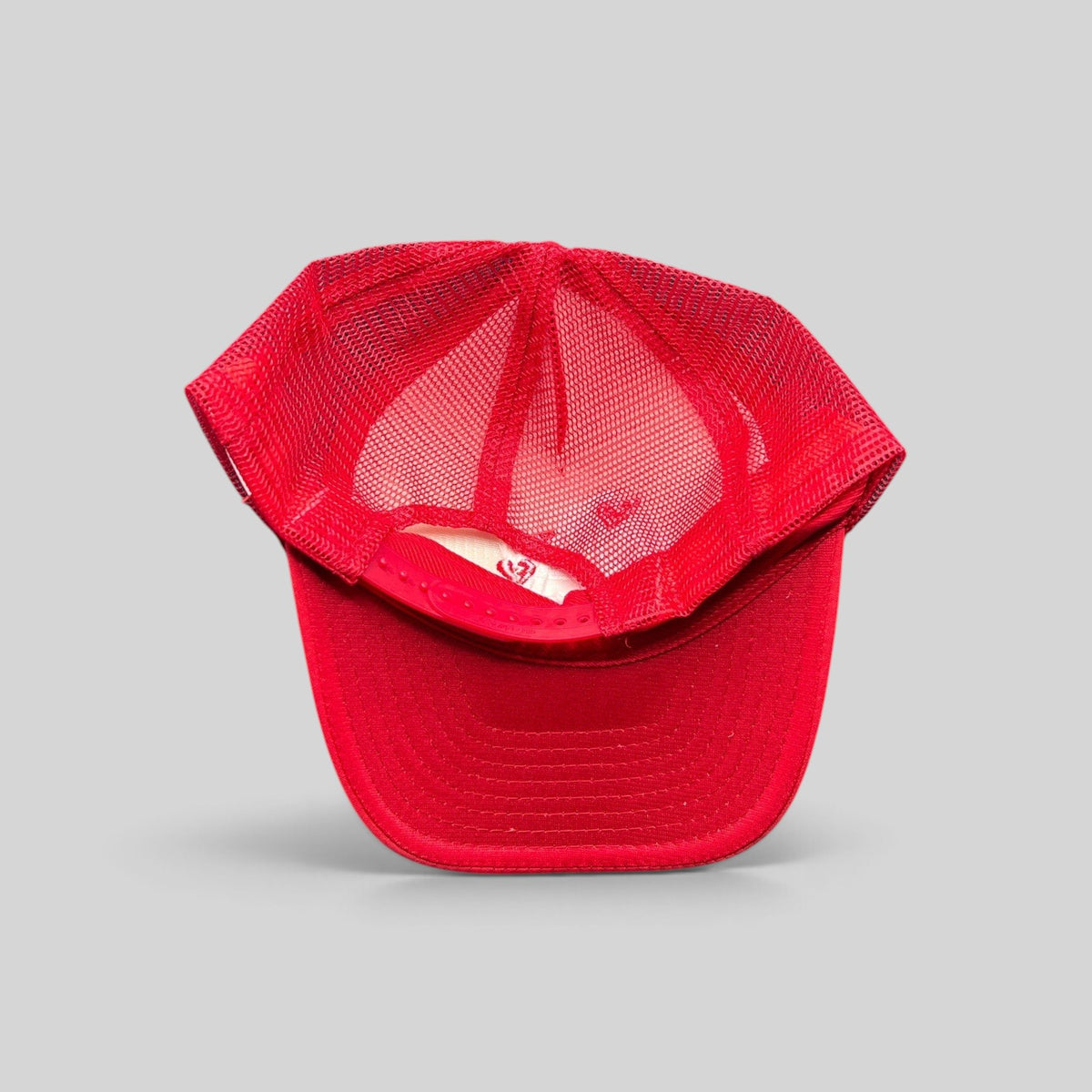 Raree Finds red Nissin Cap trucker hat with breathable mesh back and adjustable snapback closure, top-down view.