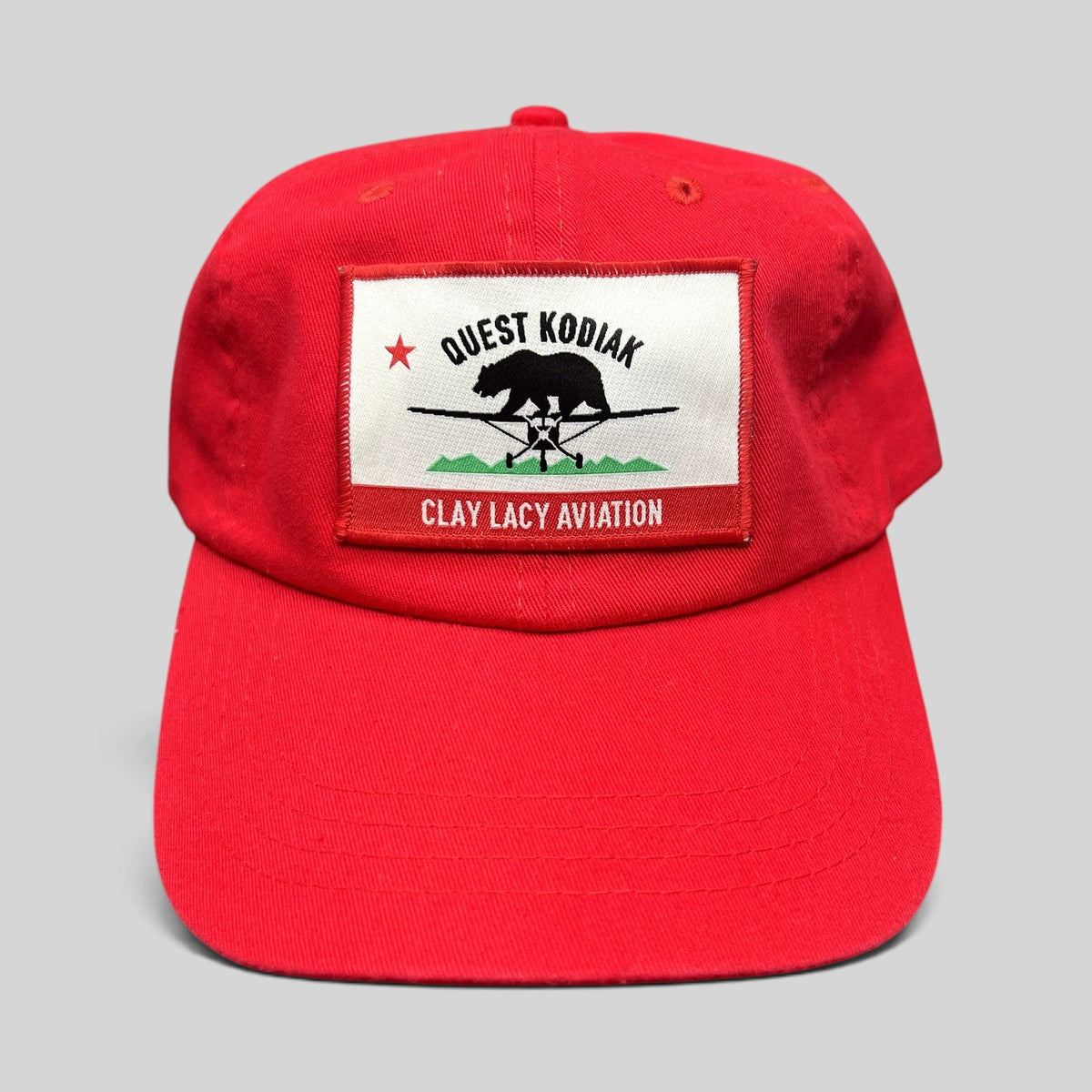 Raree Finds bright red cotton strapback hat with a woven Quest Kodiak and Clay Lacy Aviation aircraft patch