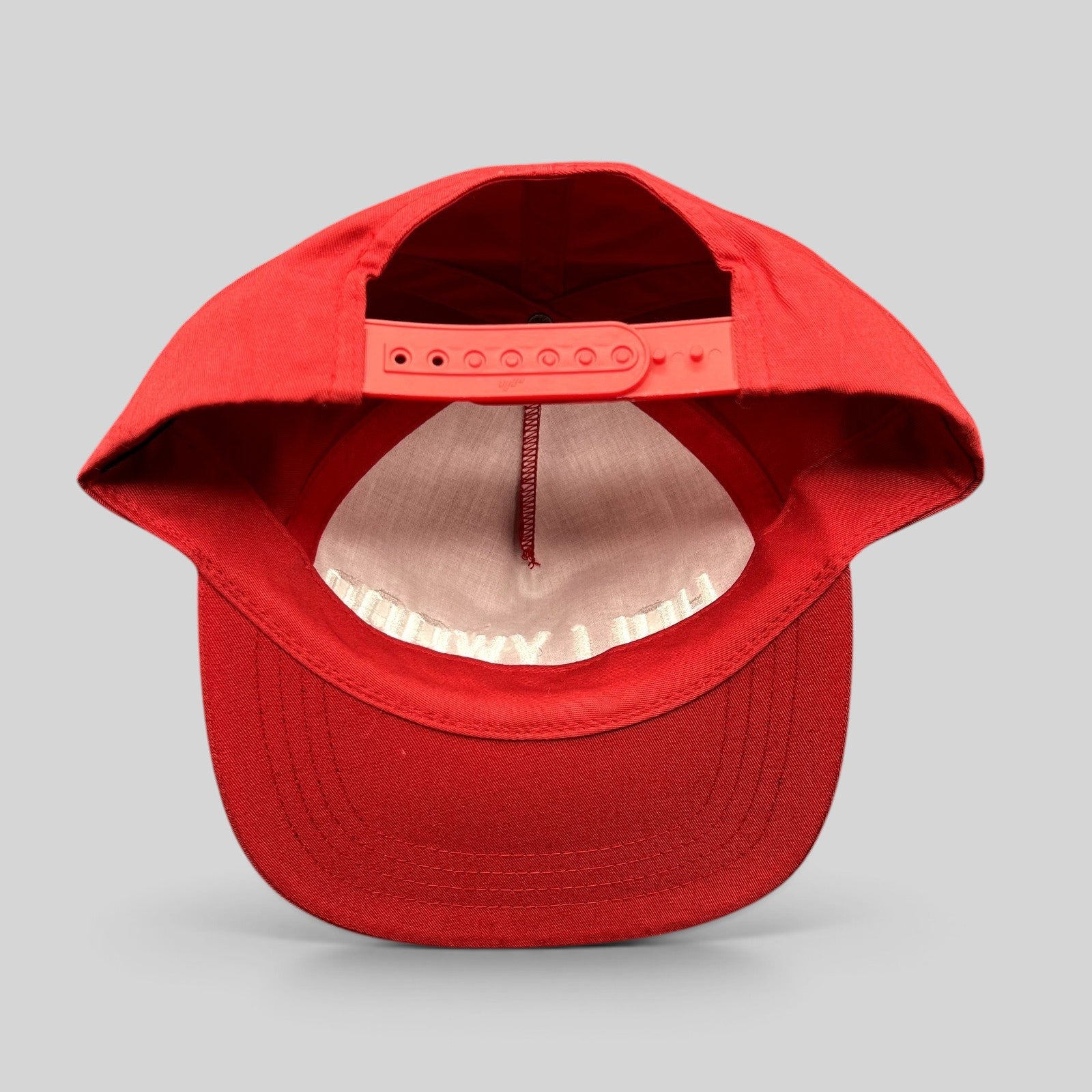 Raree Finds red Yupoong snapback hat showing the interior adjustable plastic strap and flat brim from the back
