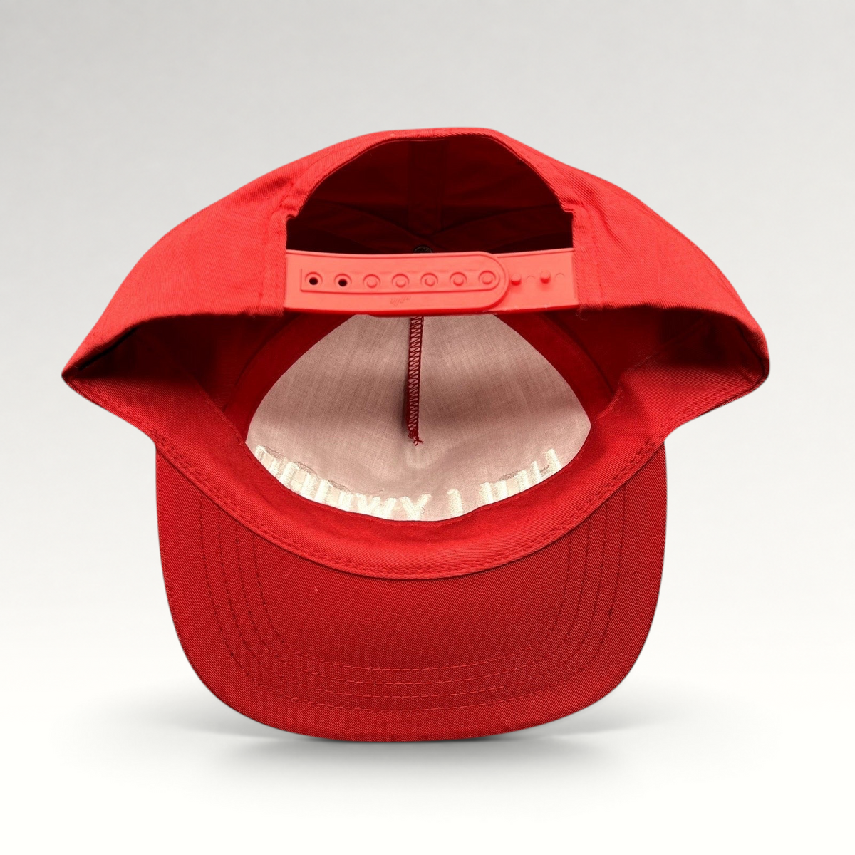 Raree Finds red Yupoong snapback hat showing the interior adjustable plastic strap and flat brim from the back