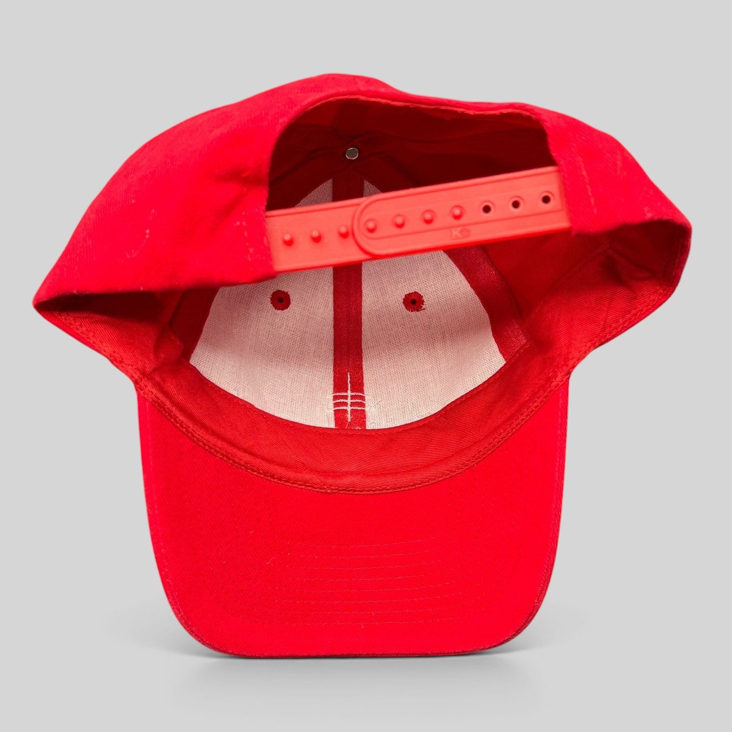 Raree Finds red cotton snapback hat with plastic adjustable strap, viewed from the back showing interior construction.