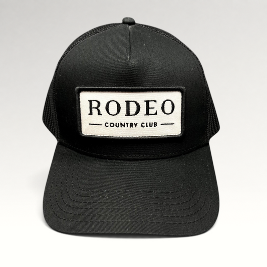Raree Finds black Rodeo Country Club trucker hat with a white embroidered patch and breathable mesh back panels.