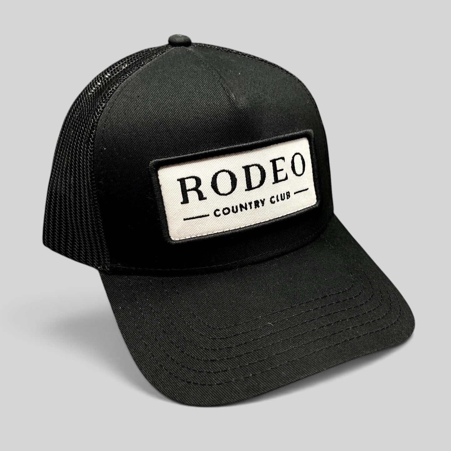 Raree Finds black Rodeo Country Club trucker hat with a white embroidered front patch and breathable mesh back