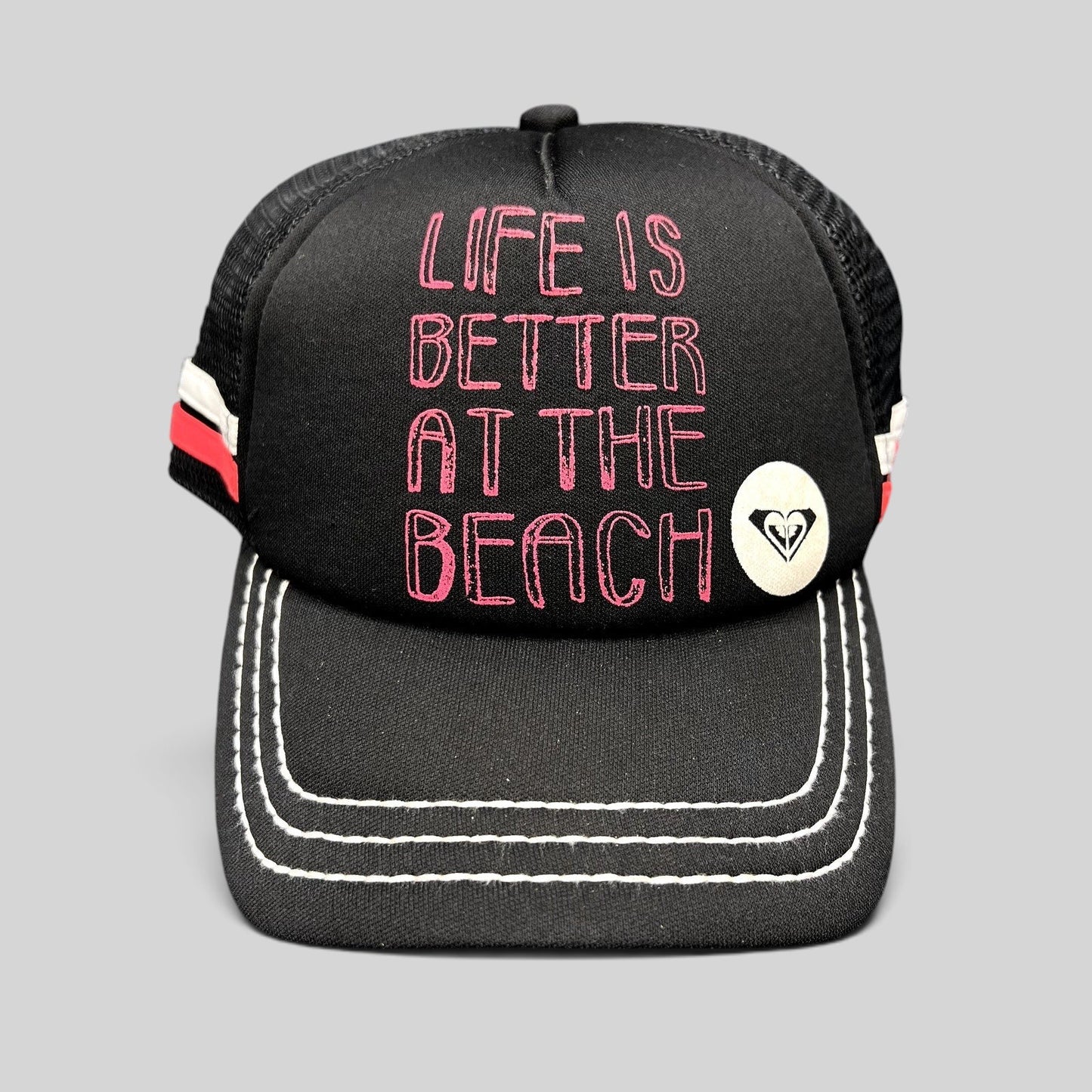 Raree Finds Roxy black trucker hat with pink Life Is Better At The Beach embroidery and white contrast brim stitching
