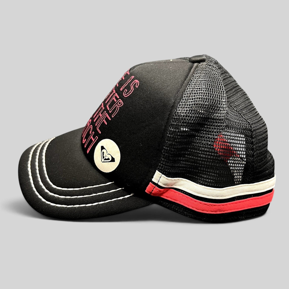 Raree Finds Roxy black trucker hat with pink embroidered text and heart logo, featuring mesh back and contrast brim.