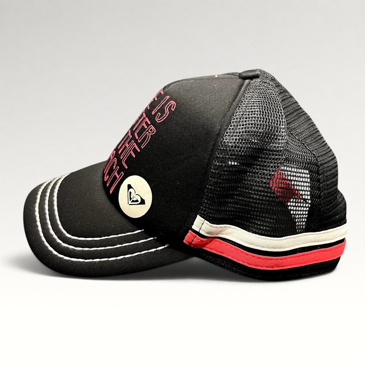 Raree Finds Roxy black trucker hat with pink embroidered text and heart logo, featuring mesh back and contrast brim.