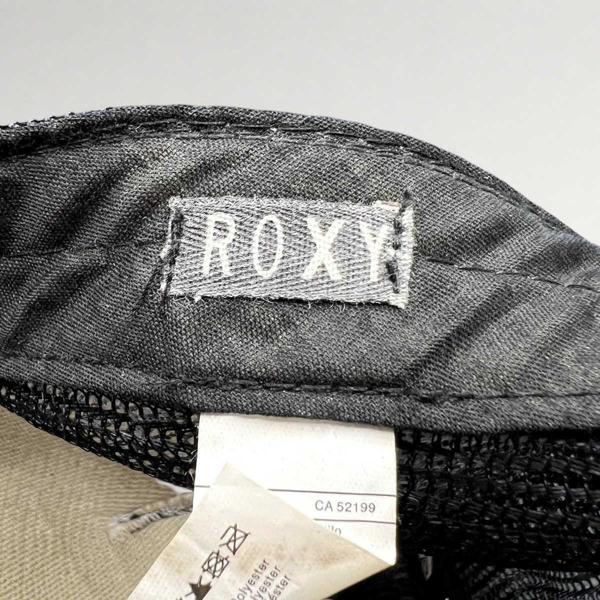 Raree Finds Roxy trucker hat interior label showing brand logo and care tag details on black mesh fabric
