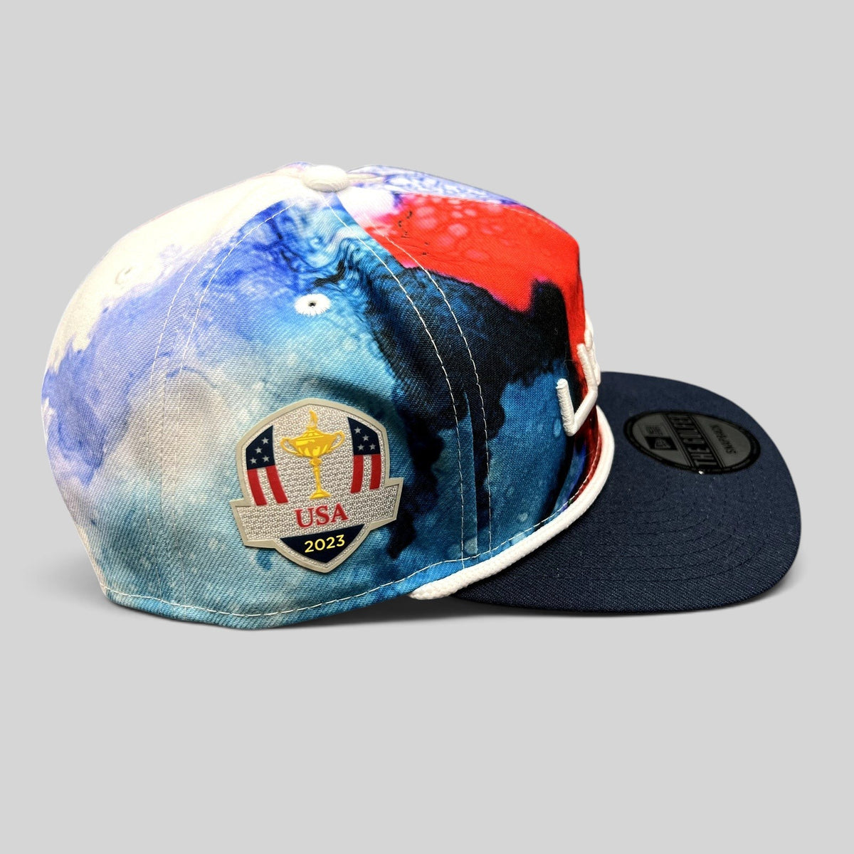 Raree Finds 2023 Ryder Cup Team USA snapback hat with red, white, and blue watercolor print and side tournament patch.