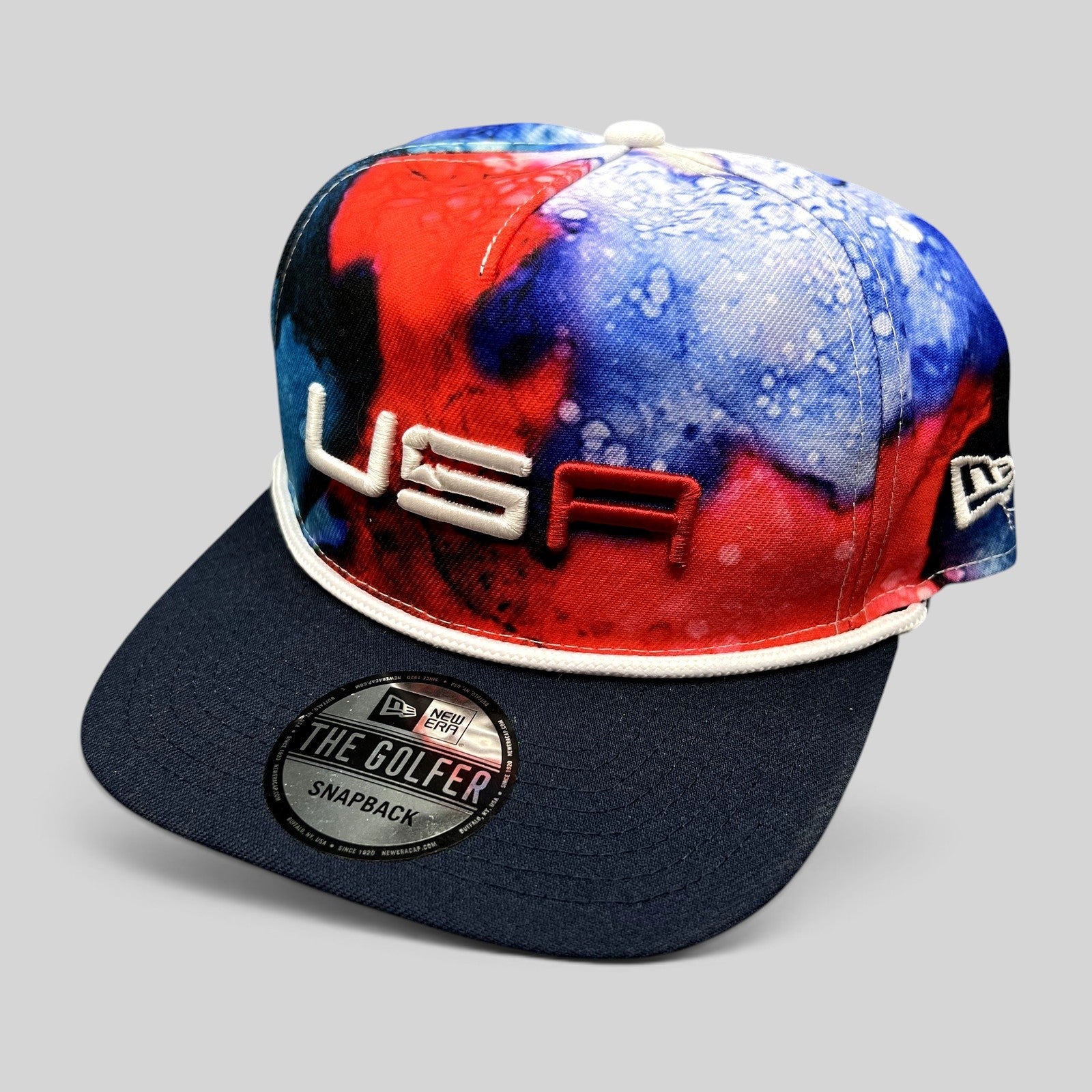 Raree Finds 2023 Ryder Cup Team USA snapback hat with red, white, and blue watercolor crown and navy brim.