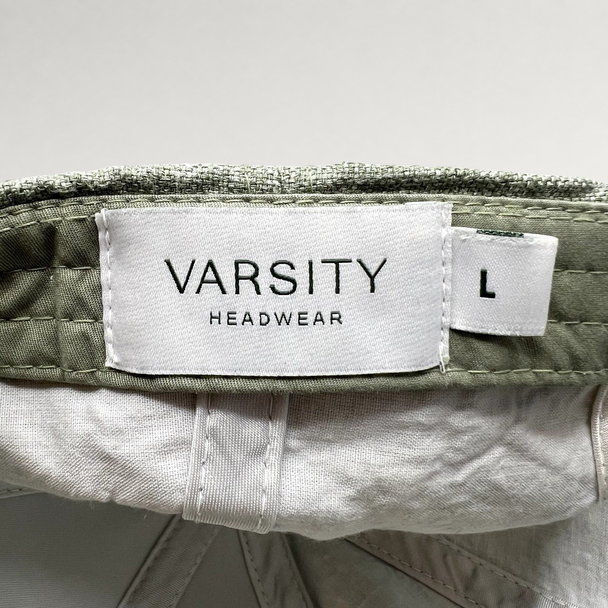 Raree Finds sage green linen cap interior label showing Varsity Headwear branding and size large tag