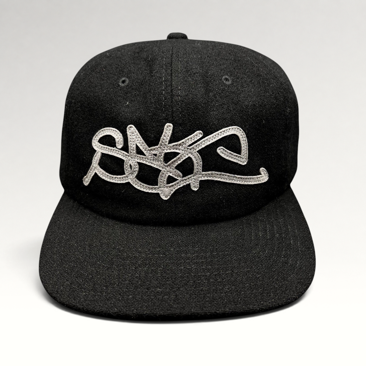 Raree Finds Sake Brand black strapback cap with oversized gray embroidered script logo on a structured wool-blend hat.