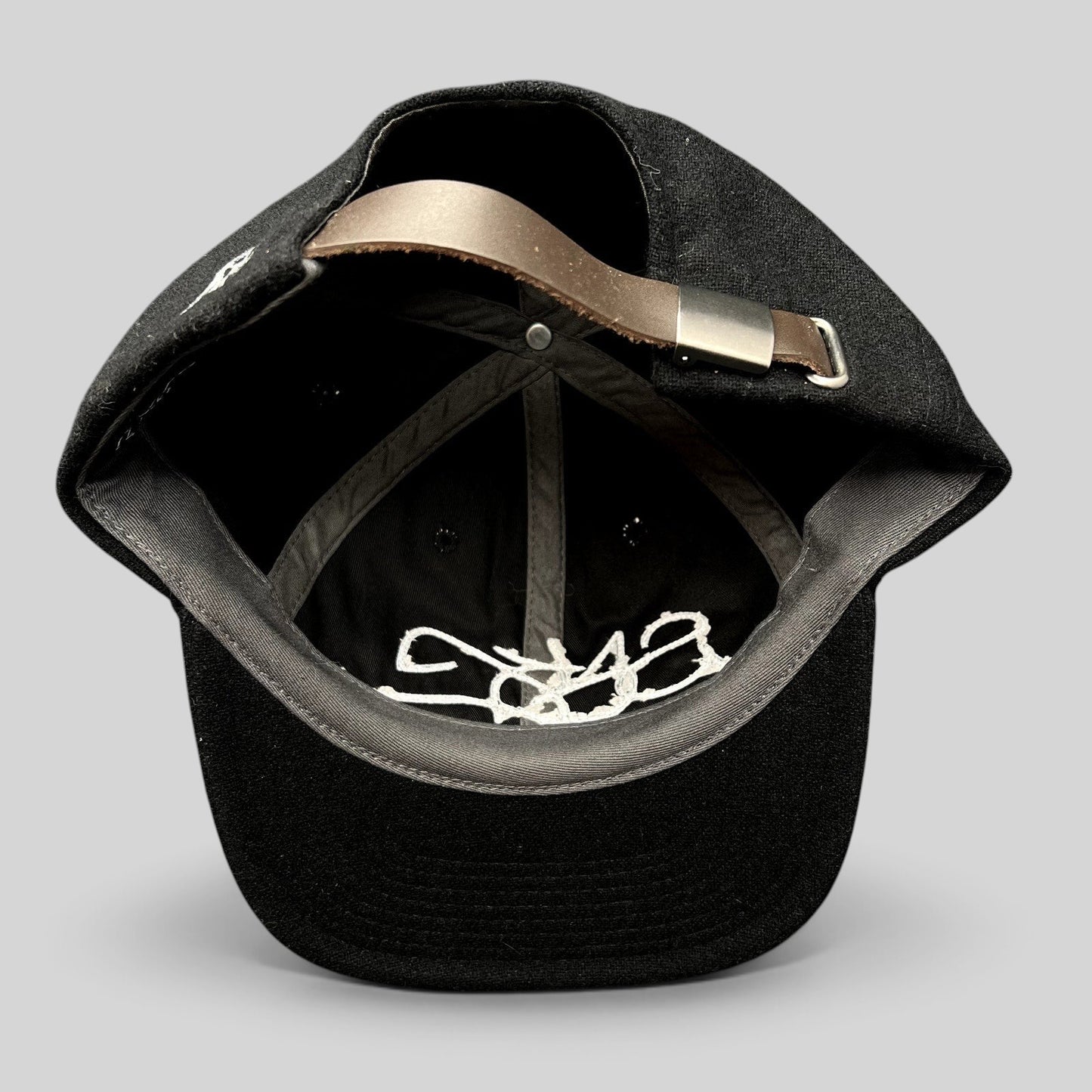 Raree Finds Sake Brand black wool-blend strapback cap showing interior details and adjustable leather strap closure.