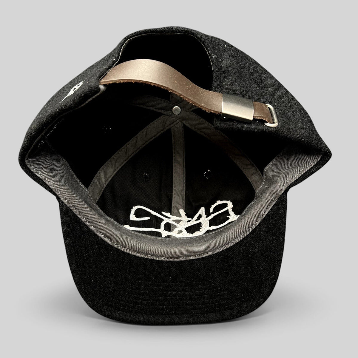 Raree Finds Sake Brand black wool-blend strapback cap showing interior details and adjustable leather strap closure.