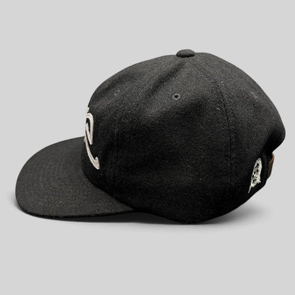 Raree Finds black Sake Brand strapback hat with gray embroidered script logo and flat brim in a side profile view.