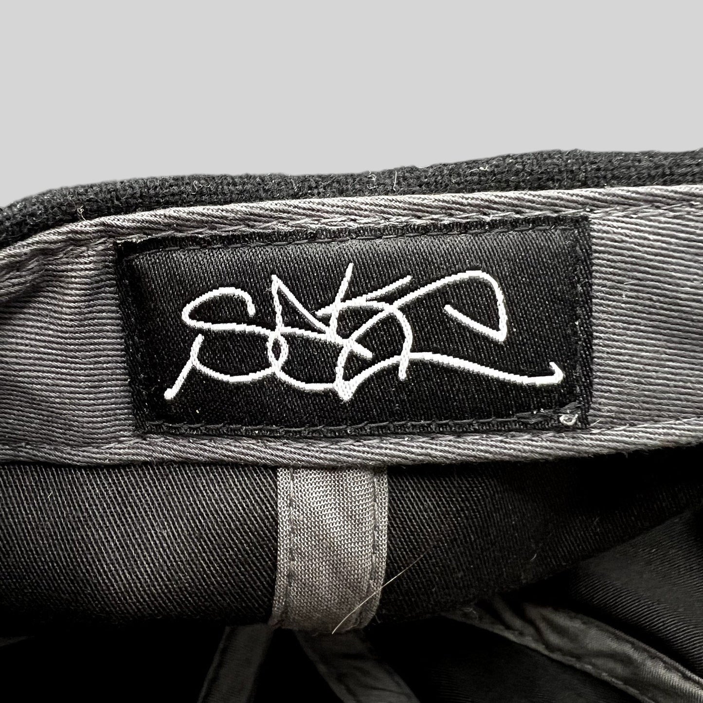 Raree Finds Sake Brand black strapback hat interior featuring a white embroidered script logo label on the crown