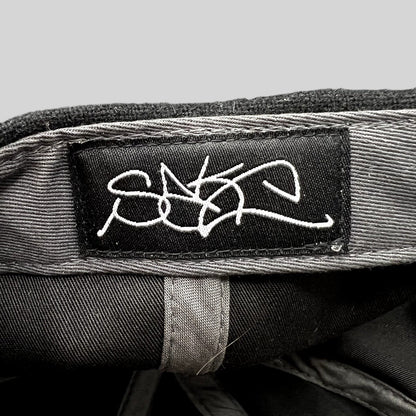 Raree Finds Sake Brand black strapback hat interior featuring a white embroidered script logo label on the crown