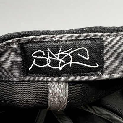 Raree Finds Sake Brand black strapback hat interior featuring a white embroidered script logo label on the crown