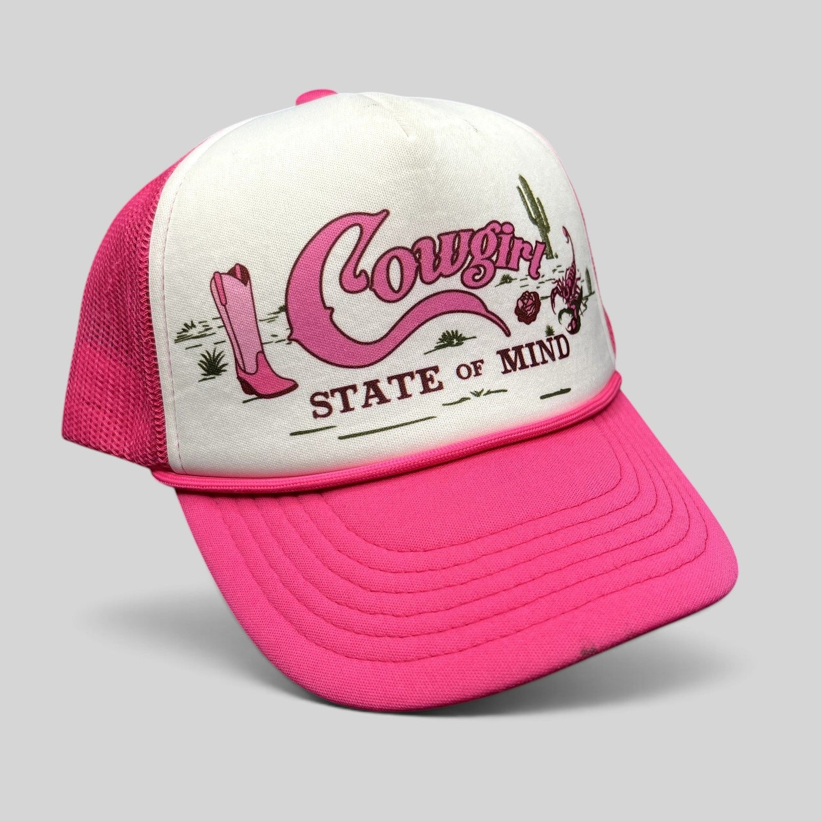 Raree Finds Shyanne pink and white trucker hat with Cowgirl State of Mind graphic, cowboy boots, and desert artwork.