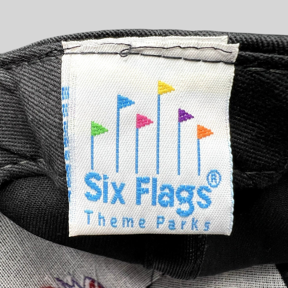 Raree Finds vintage Six Flags Theme Parks woven clothing label with colorful flag icon on black fabric