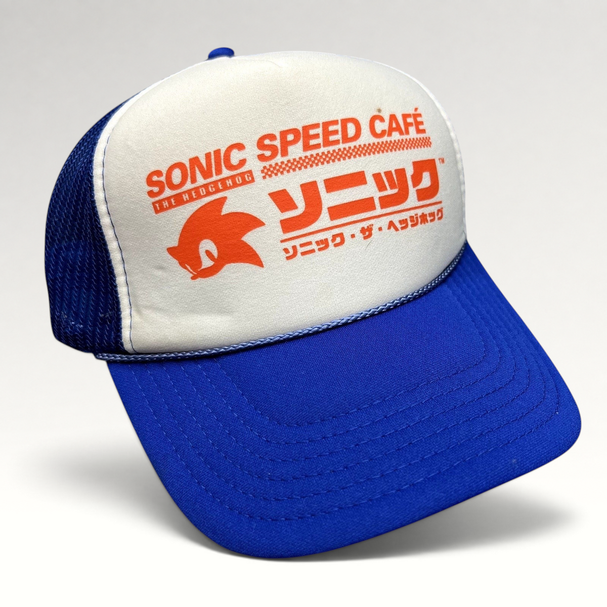 Raree Finds Sonic Speed Café trucker hat with white foam front, blue mesh back, and orange Japanese Sonic logo graphic.