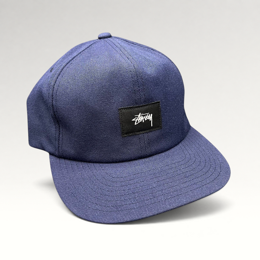 Raree Finds navy Stussy strapback hat with a black box logo patch and white script embroidery on a flat brim cap.